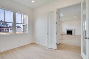Empty room featuring light wood finished floors, recessed lighting, and a fireplace