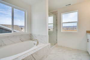 Full bath with light marble finish floors, vanity, a marble finish shower, and a bath