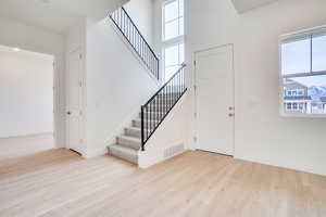 Foyer with a high ceiling, stairs, light wood-type flooring, and plenty of natural light