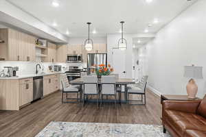 Kitchen featuring light brown cabinetry, open shelves, modern cabinets, tasteful backsplash, and hanging light fixtures