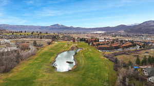 View of property location featuring a water and mountain view, nearby suburban area, and a local golf course