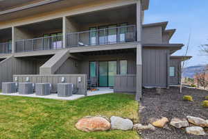 Back of house featuring a patio, board and batten siding, a balcony, and a lawn