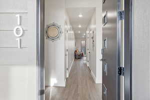 Hallway with wood finished floors and recessed lighting