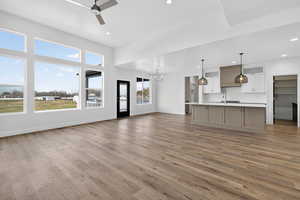 Unfurnished living room featuring a chandelier, ceiling fan, light wood-style floors, and recessed lighting