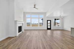 Unfurnished living room featuring a glass covered fireplace, a chandelier, a ceiling fan, light wood-type flooring, and recessed lighting