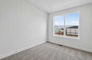 Empty room featuring light colored carpet and baseboards