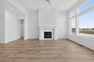 Unfurnished living room featuring a glass covered fireplace, light wood-style floors, recessed lighting, and ceiling fan