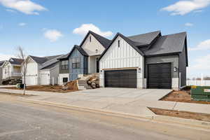 Modern farmhouse featuring driveway, board and batten siding, a shingled roof, a residential view, and brick siding