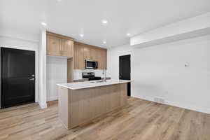 Kitchen with light brown cabinetry, a center island with sink, stainless steel appliances, recessed lighting, and light wood-style floors