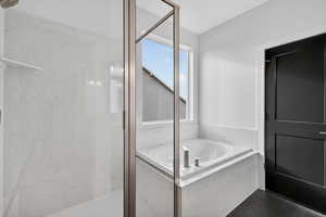 Bathroom featuring a garden tub and a marble finish shower