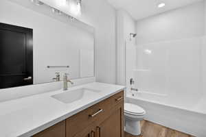 Bathroom featuring vanity, washtub / shower combination, and light wood-type flooring