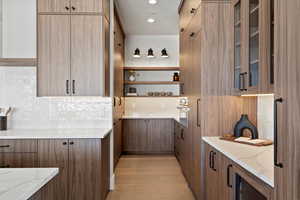 Kitchen featuring open shelves, light stone counters, modern cabinets, glass insert cabinets, and stainless steel oven