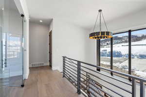 Hallway featuring an upstairs landing, light wood-style flooring, and recessed lighting