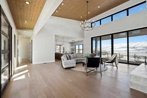 Living area featuring wooden ceiling, light wood-type flooring, recessed lighting, a chandelier, and a high ceiling