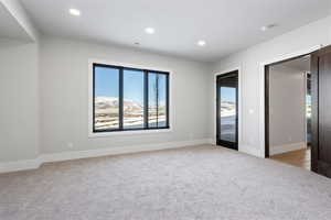 Unfurnished bedroom featuring access to exterior, light carpet, recessed lighting, and a mountain view
