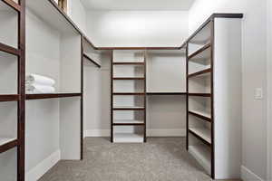 Walk in closet with light colored carpet