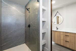 Bathroom with double vanity and a marble finish shower