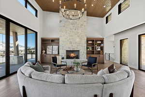 Living room with wood ceiling, wood-type flooring, a fireplace, a towering ceiling, and recessed lighting