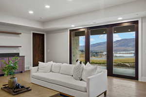 Living room featuring recessed lighting, a water and mountain view, light wood-style flooring, and a fireplace