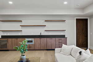 Kitchen with open shelves, recessed lighting, wine cooler, light wood-style flooring, and modern cabinets