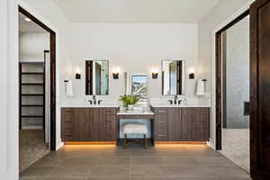 Full bath featuring double vanity, a spacious closet, and light tile patterned flooring