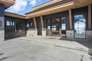 Entrance to property featuring stone siding and a patio
