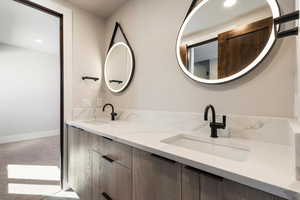Full bathroom with double vanity, recessed lighting, and light carpet