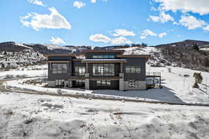 Snow covered property featuring a mountain view and stone siding