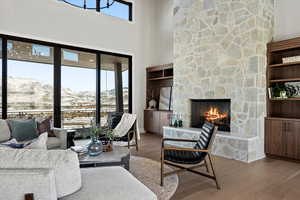 Living room featuring built in features, a mountain view, wood finished floors, a towering ceiling, and a fireplace
