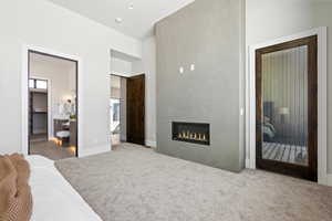Carpeted bedroom with a glass covered fireplace, ensuite bath, and access to outside