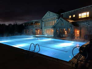 Pool at night featuring a community pool, a patio, and a balcony