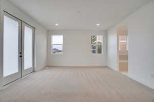 Unfurnished room featuring french doors, healthy amount of natural light, light colored carpet, and recessed lighting