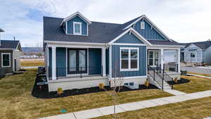 View of front of home with board and batten siding, a shingled roof, a front lawn, and a porch