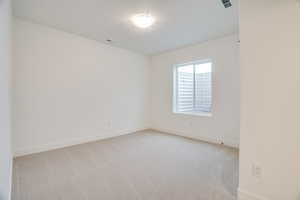 Spare room featuring light colored carpet and baseboards