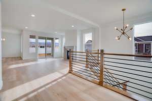 Hall featuring a chandelier, light wood-type flooring, an upstairs landing, and recessed lighting