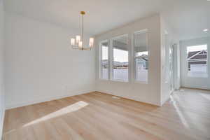 Unfurnished dining area featuring light wood-style floors and a chandelier