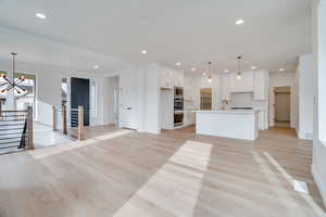 Unfurnished living room featuring light wood-style floors, a chandelier, and recessed lighting