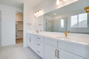 Full bathroom with double vanity, a walk in closet, a stall shower, and light tile patterned floors
