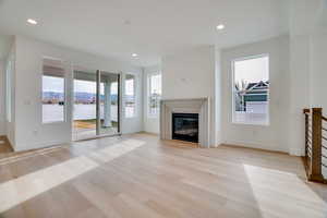 Unfurnished living room with light wood finished floors, a mountain view, a glass covered fireplace, and recessed lighting