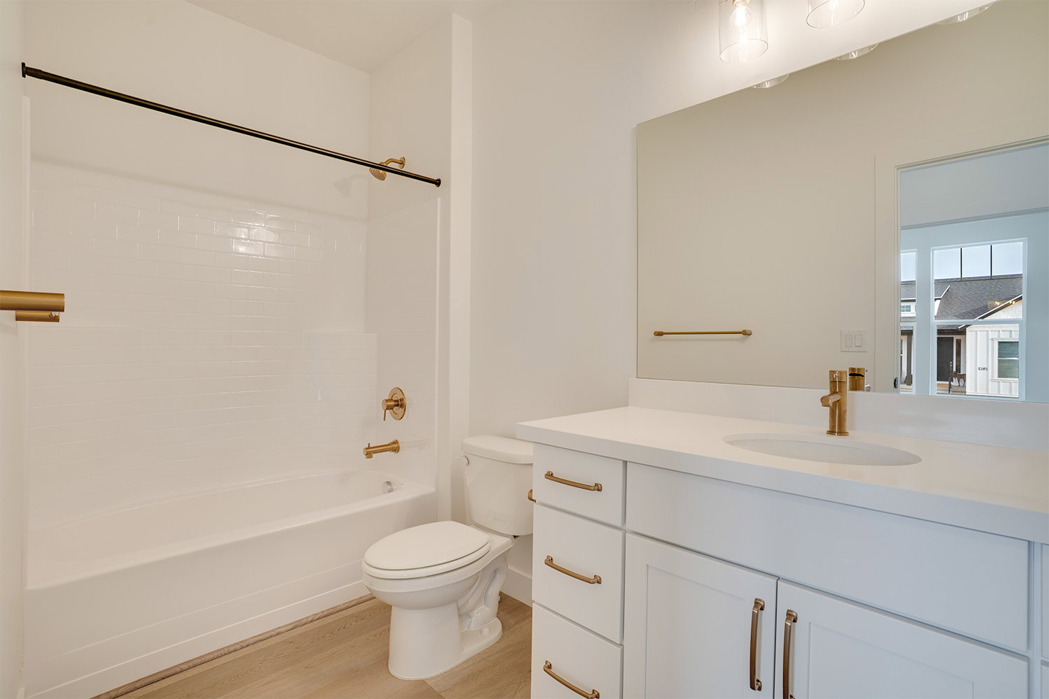 Full bath featuring washtub / shower combination, vanity, and light wood-type flooring