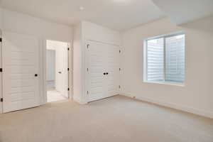 Unfurnished bedroom featuring light colored carpet and a closet
