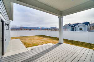 Wooden deck with a mountain view, a fenced backyard, and a patio area