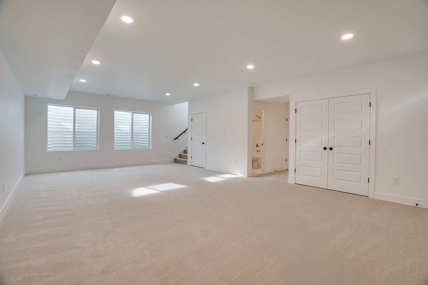 Below grade area featuring stairway, recessed lighting, and light colored carpet