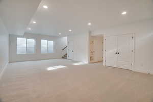 Below grade area featuring stairway, recessed lighting, and light colored carpet