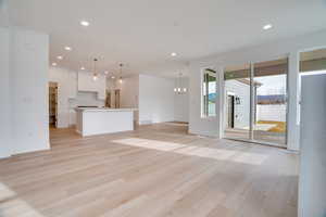 Unfurnished living room with light wood finished floors, a chandelier, and recessed lighting