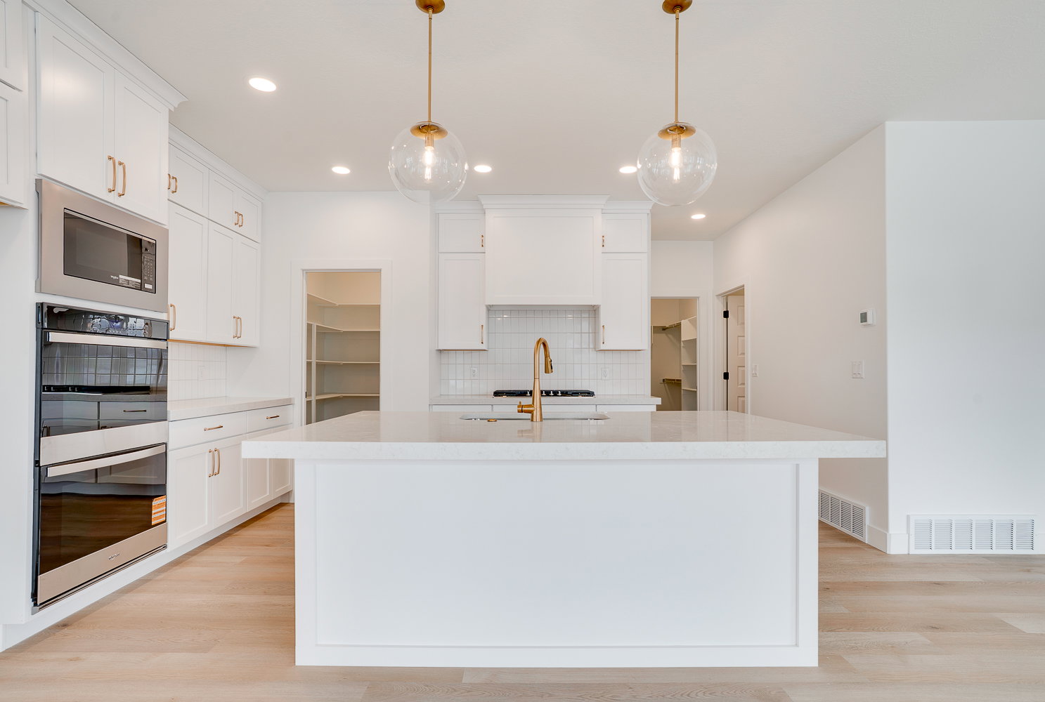 Kitchen with light stone countertops, appliances with stainless steel finishes, a kitchen island with sink, white cabinets, and recessed lighting
