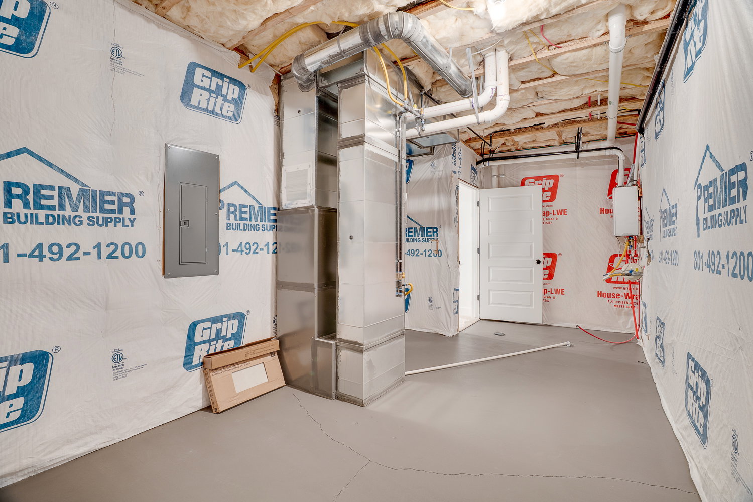Utility room featuring electric panel and heating unit