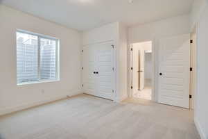 Unfurnished bedroom featuring light colored carpet and a closet