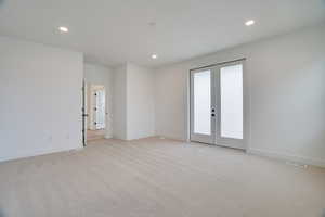 Empty room featuring french doors, light colored carpet, and recessed lighting
