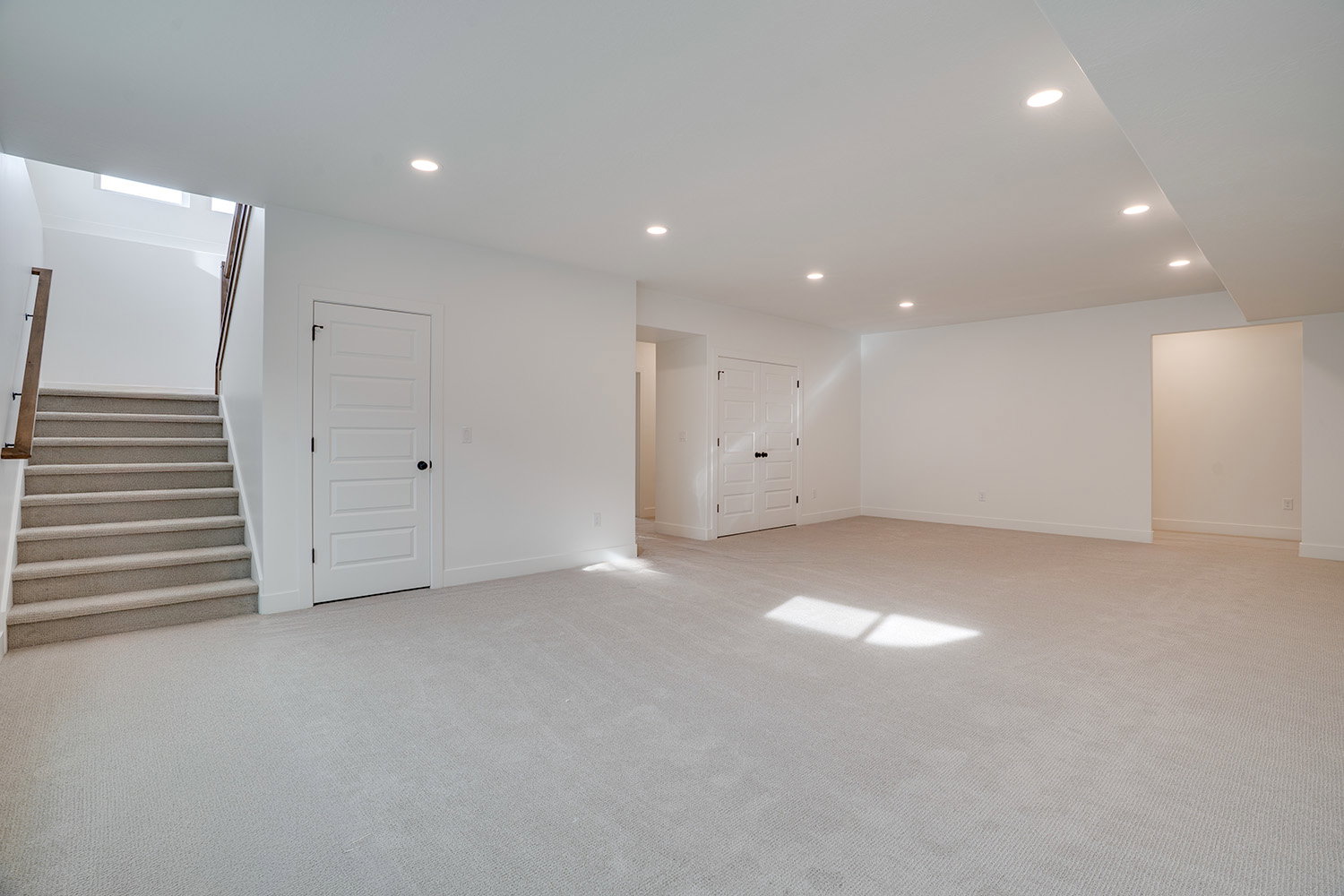 Below grade area with recessed lighting, light colored carpet, and stairway